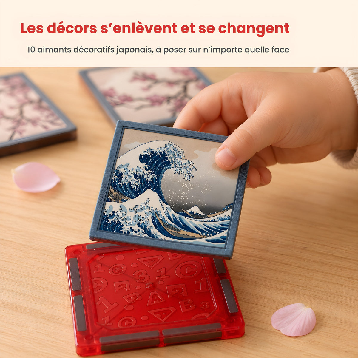 Une main d'enfant retire l'aimant décoratif Grande Vague posé sur un bloc magnétique rouge